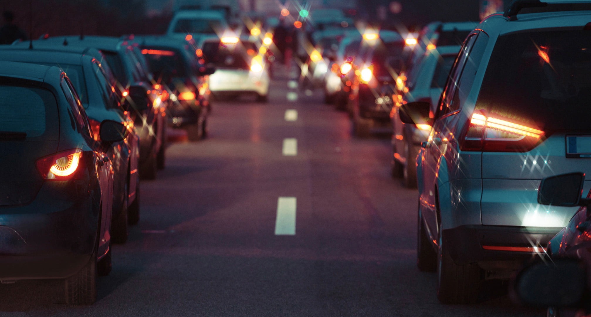 Lichtstrahlen, die durch die Mitte der Rücklichter eines Autos verlaufen, illustrieren Astigmatismus bei Nacht (links). Klare Auto-Rücklichter bei Nacht, gesehen von einem normalen Auge (rechts)