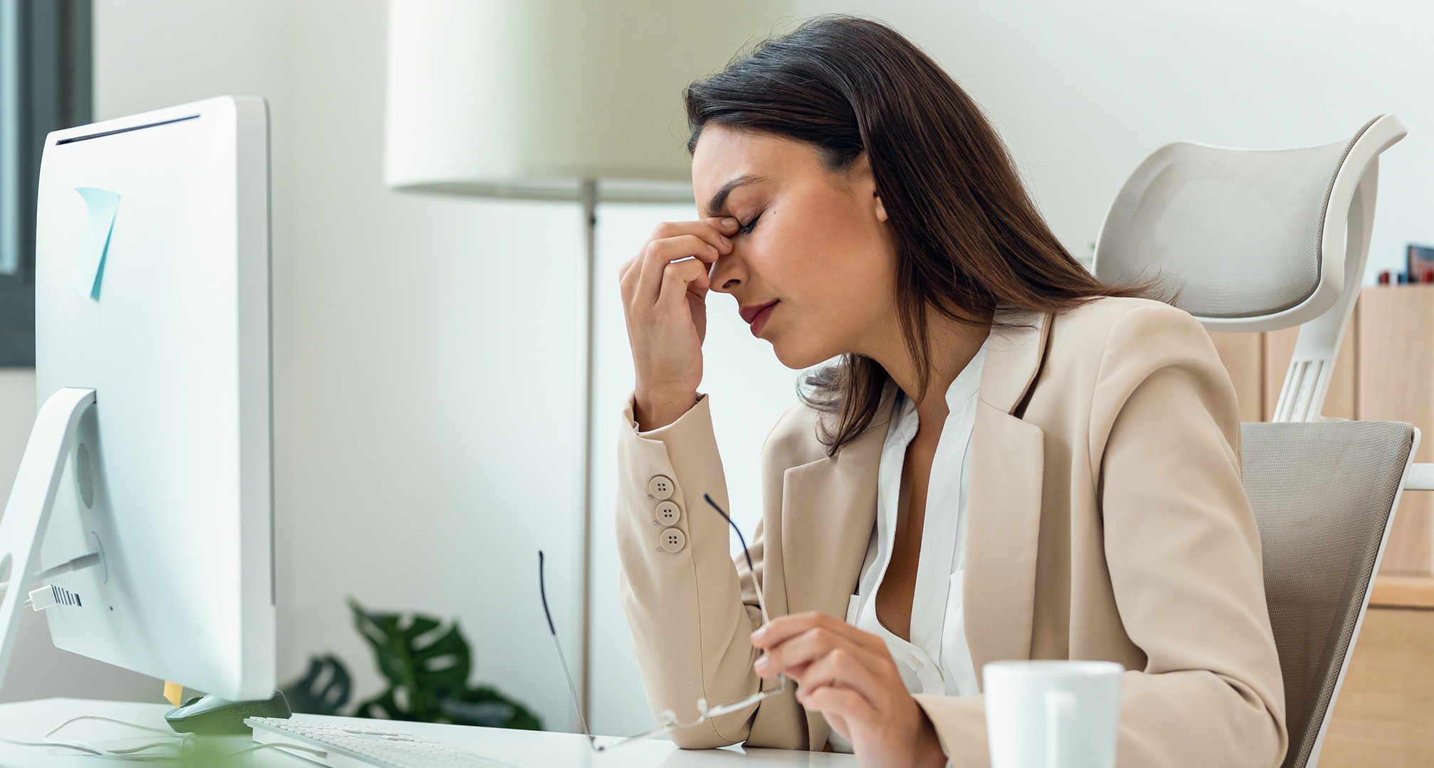 personne plissant les yeux à cause de la fatigue oculaire à un bureau avec des lunettes