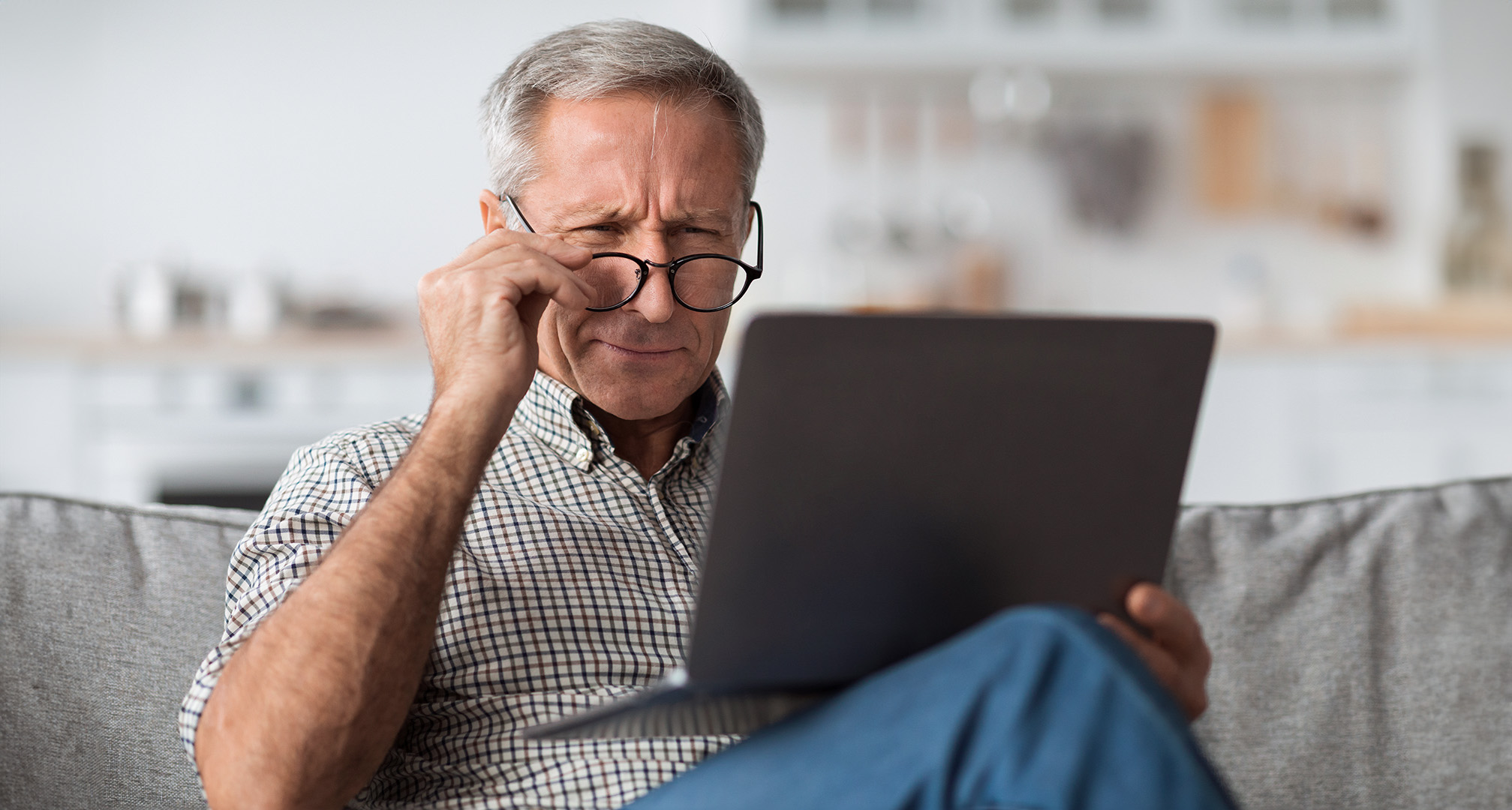 Person mit Brille, die auf einen Laptop blinzelt