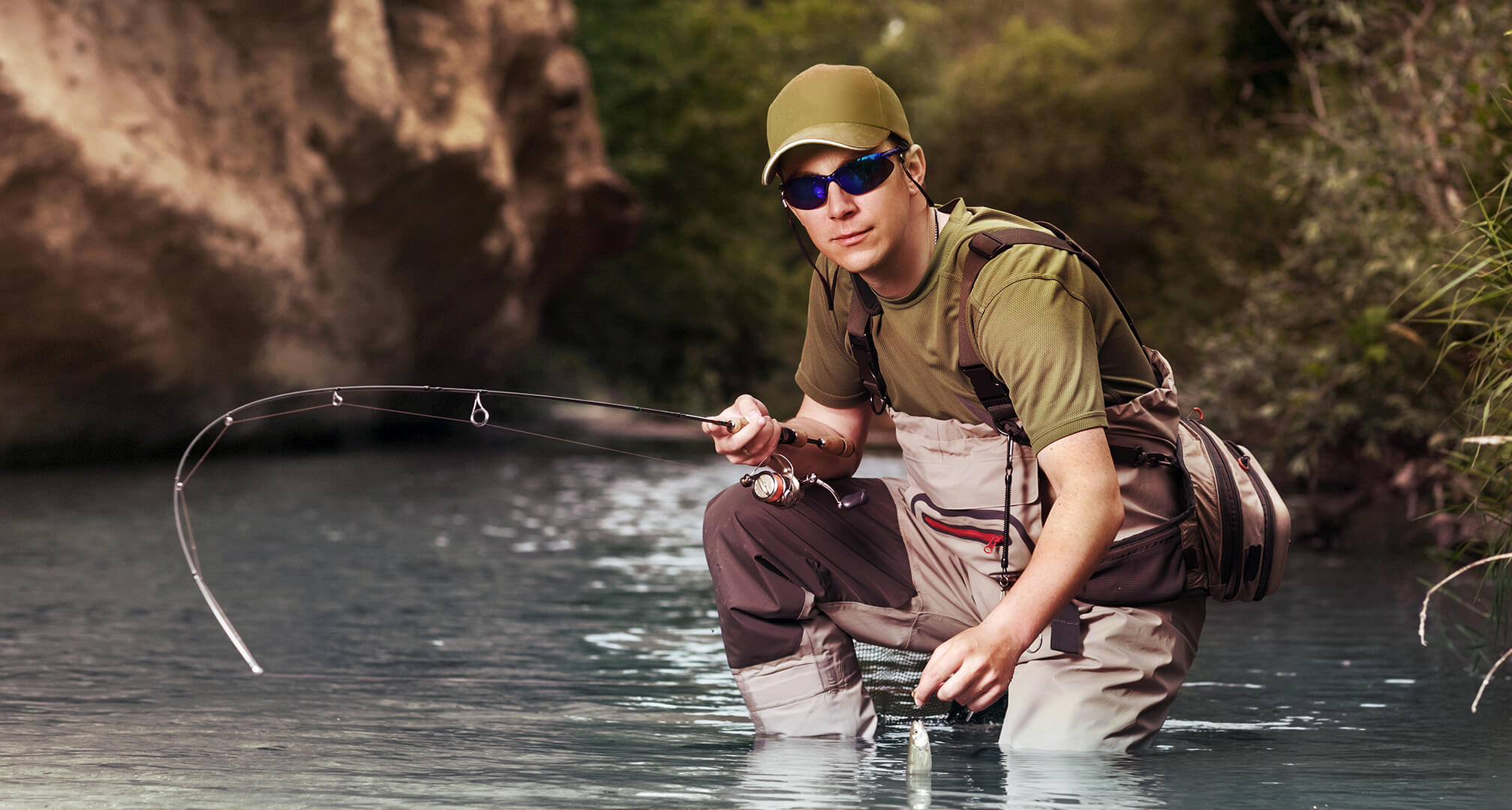 pêcheur agenouillé dans l'eau avec des lunettes de soleil