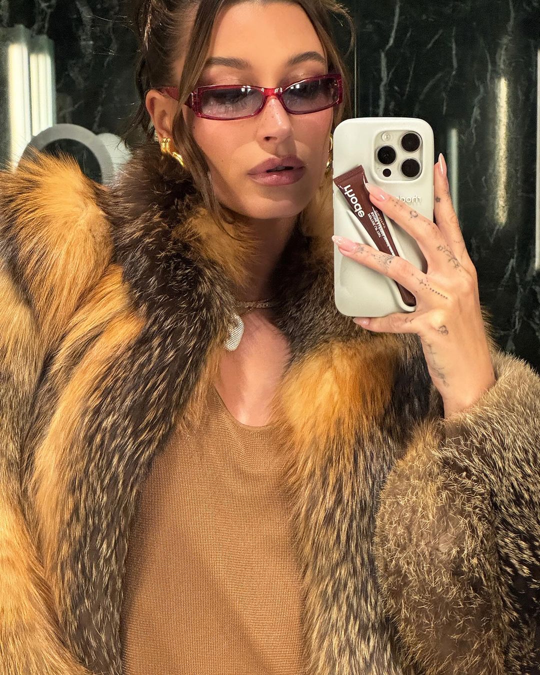 hailey bieber se prend en photo dans le miroir avec des lunettes de soleil